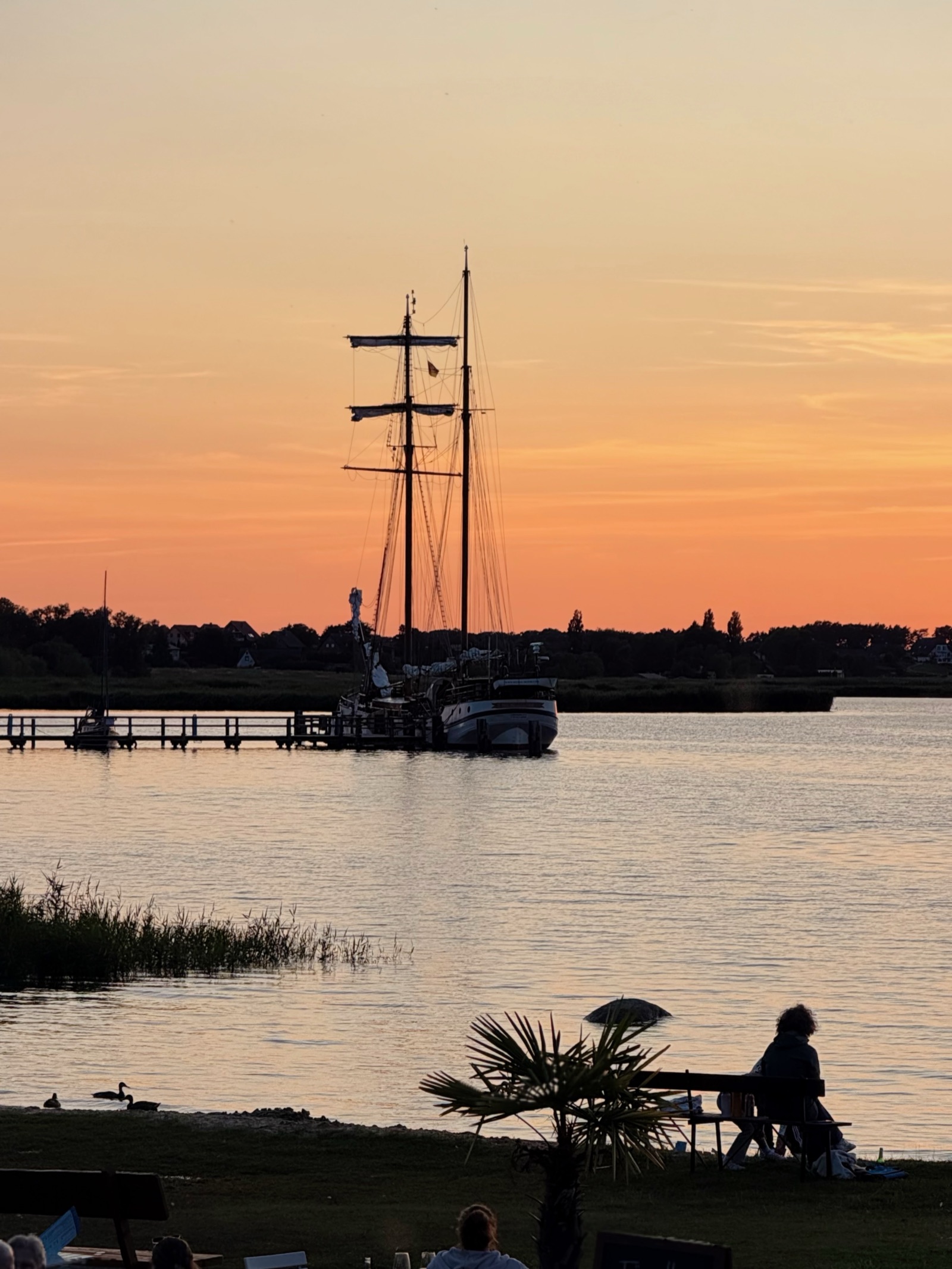 Zweimaster — Segelschiff in der Dämmerung am Steg, oranger Sonnenuntergang, Usedom