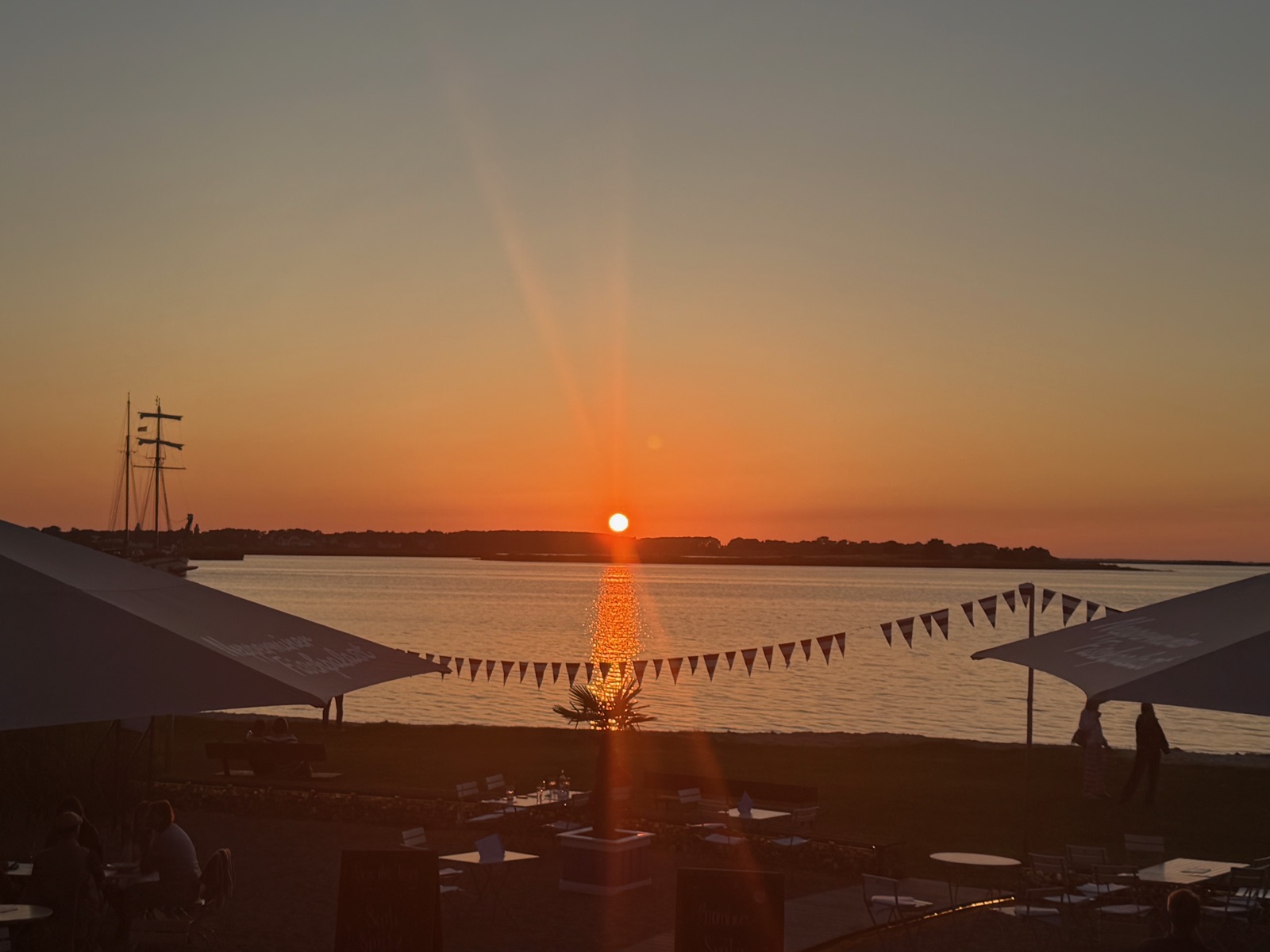 Letztes Licht — Sonnenuntergang am Horizont mit Wimpelkette und Segelmast, Achterwasser Usedom