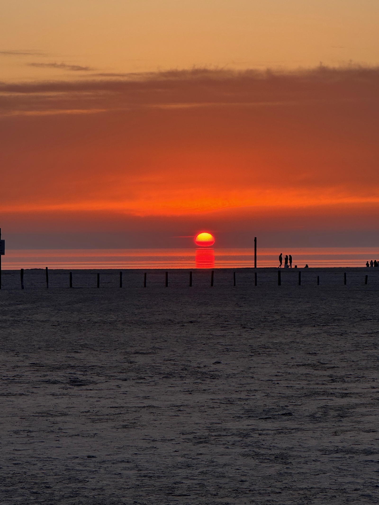 Rote Stunde — glutrote Sonne über dem Wattenmeer mit Menschen als Silhouetten, St. Peter-Ording