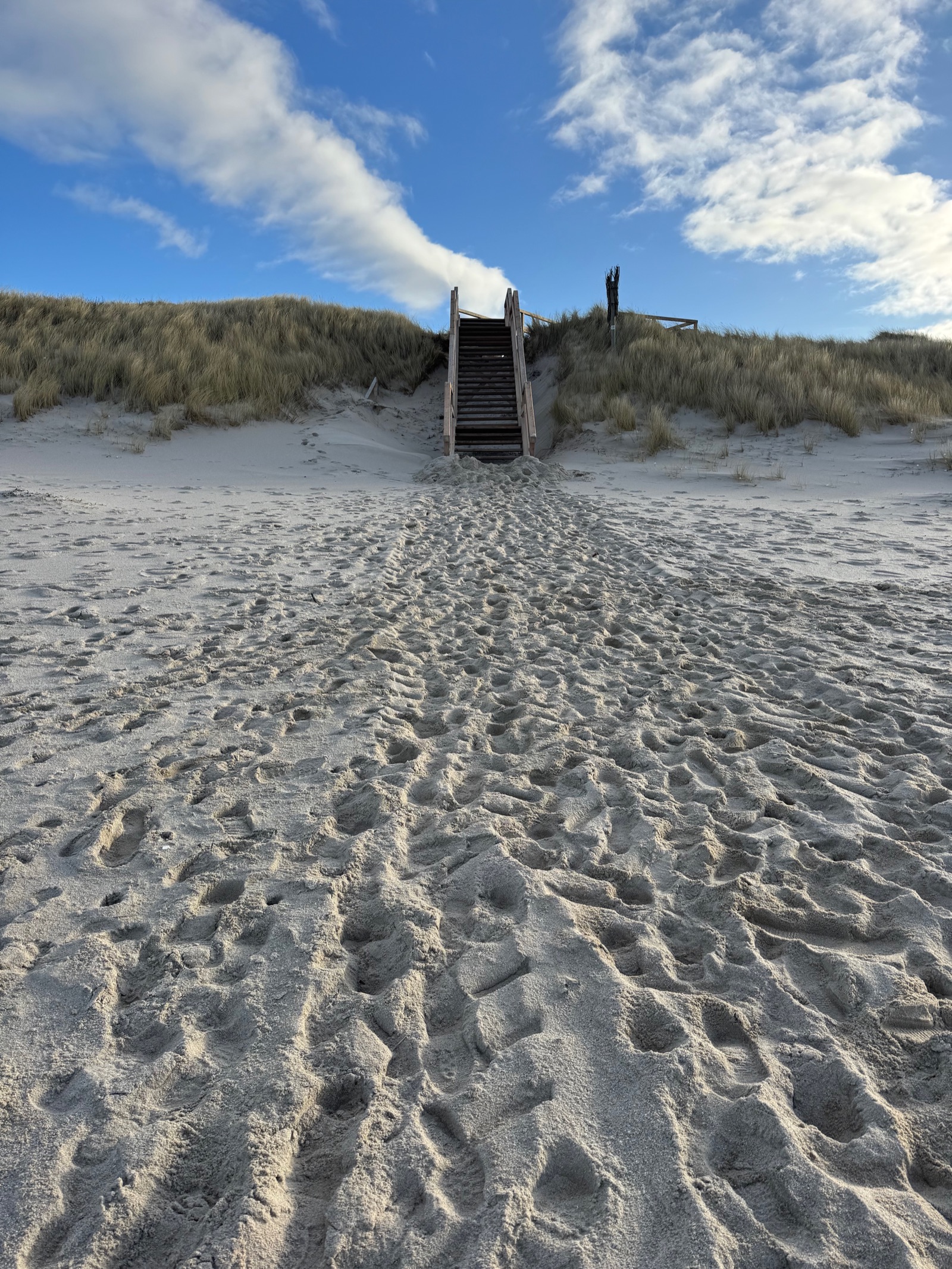 Dünenweg — hölzerne Treppe über die Düne zum Meer unter weitem Wolkenhimmel, Sylt