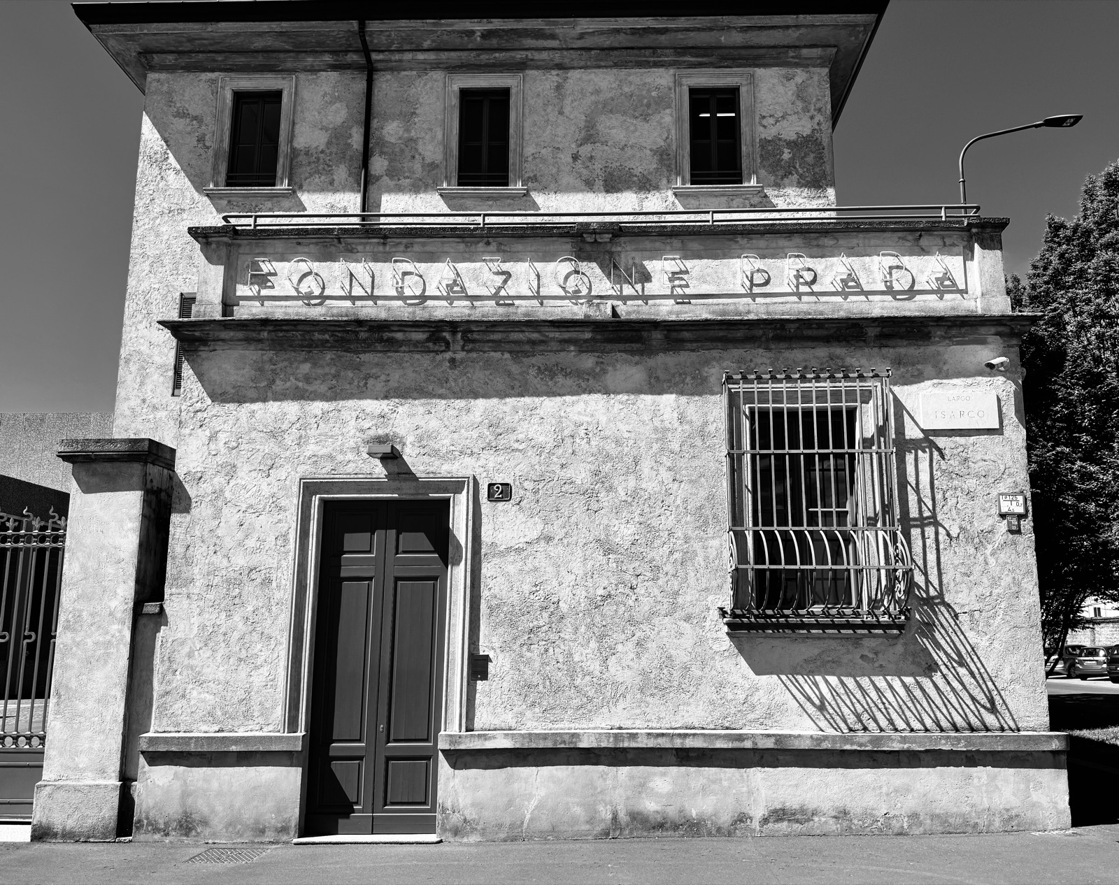 Fassade — Die raue Putzfassade der Fondazione Prada in der Mittagssonne, der Schriftzug in verwaschenen Lettern · Randlicht Fotografie