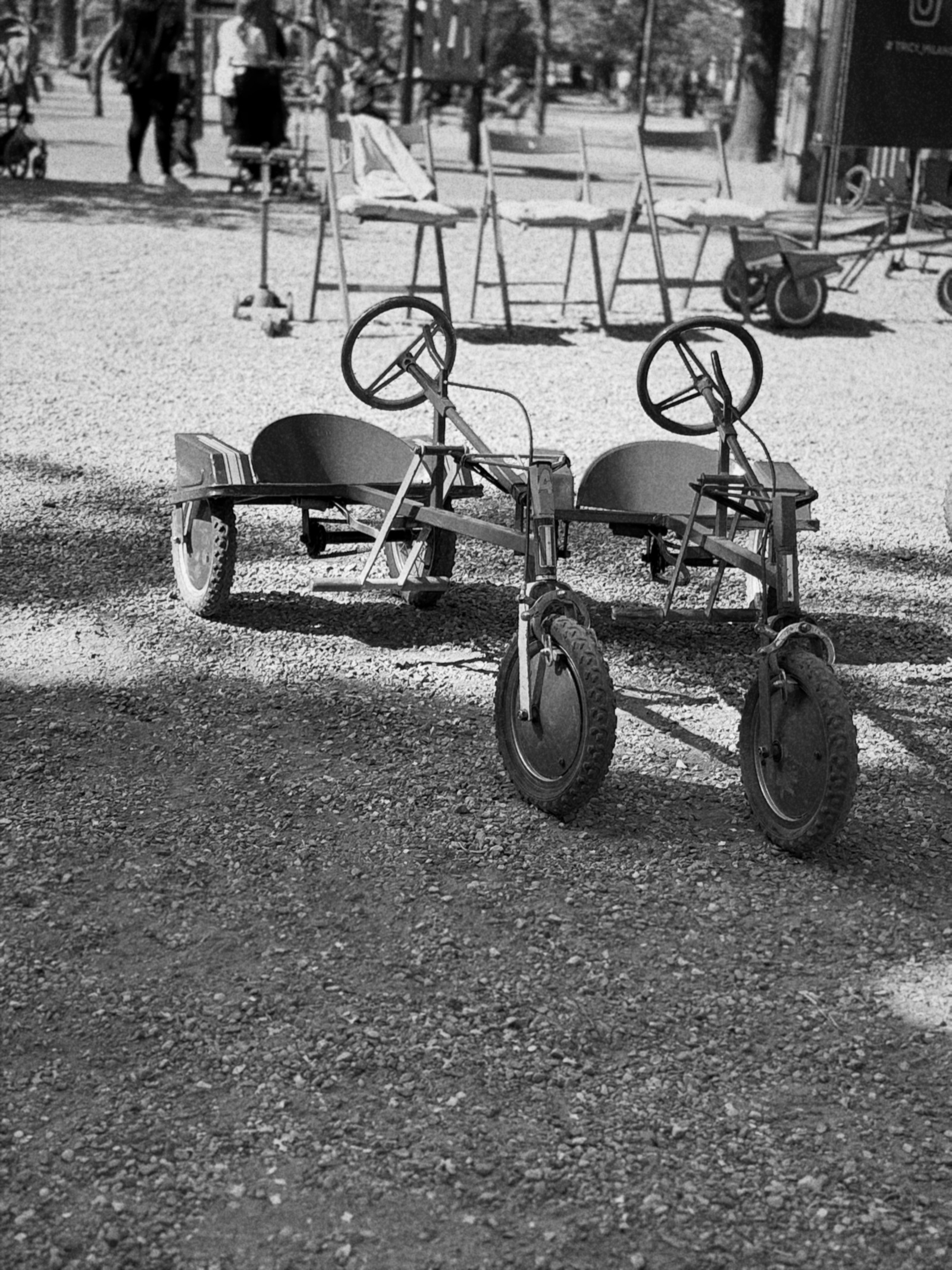 Ruhetag — Zwei ausrangierte Tretautos auf hellem Kies, Schwarzweiß — ein stiller, nostalgischer Moment mitten in der Stadt · Randlicht Fotografie